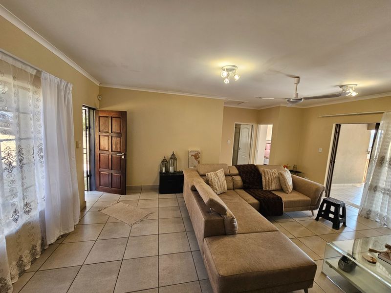 Spacious living room featuring tiled flooring, ceiling fans, and direct access to exterior areas through a solid wood door.