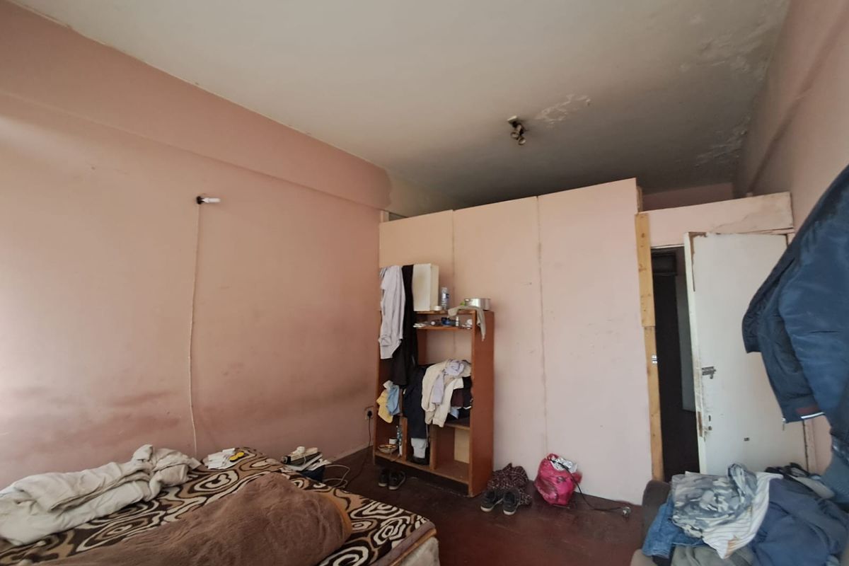 A bedroom featuring a partition wall, showing significant signs of wear including wall staining and ceiling damage, requiring renovation and cosmetic updates.