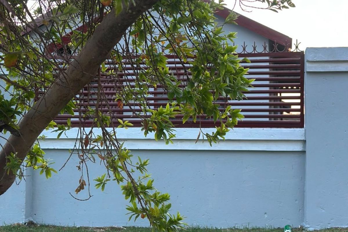A view of the rear garden featuring a solid boundary wall with integrated metal slat fencing and a well-maintained lawn area.