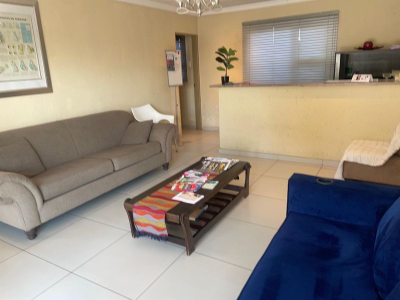 Open plan living area featuring tiled flooring, a breakfast counter, and neutral wall finishes, offering a functional space for relaxation and dining.