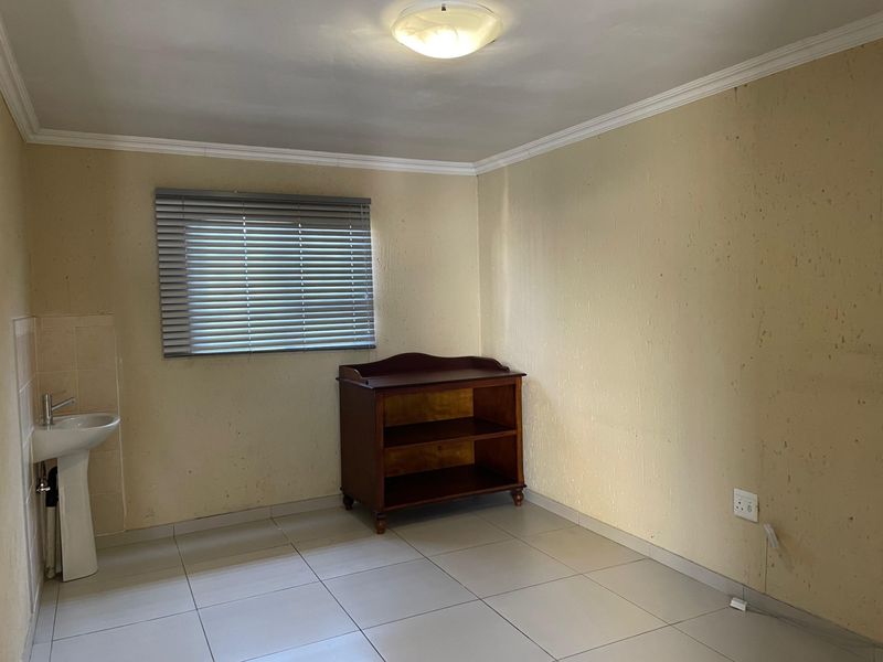 A bedroom featuring tiled flooring, a pedestal basin, and venetian blinds, requiring cosmetic updates to the wall finishes.