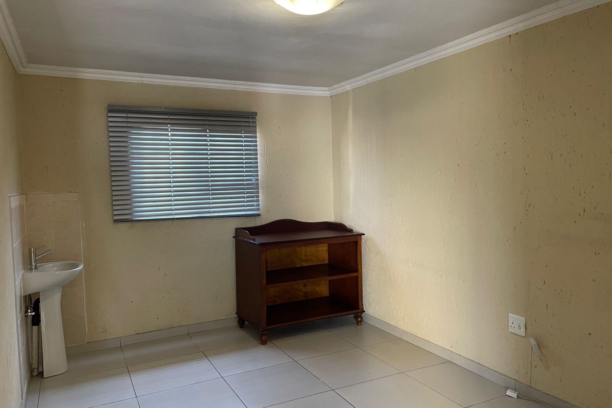 A bedroom featuring tiled flooring, a pedestal basin, and venetian blinds, requiring cosmetic updates to the wall finishes.