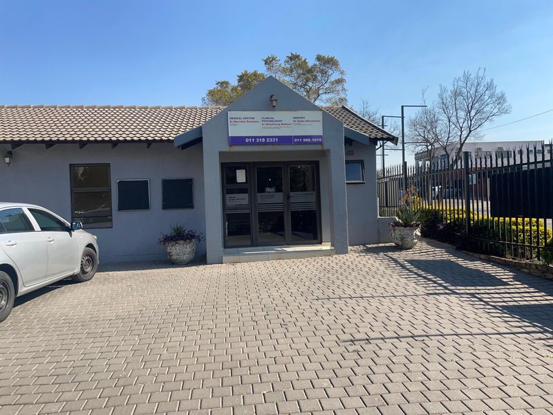 Front elevation of a commercial property featuring a paved driveway, tiled roof, and secure aluminium-framed glass entrance.