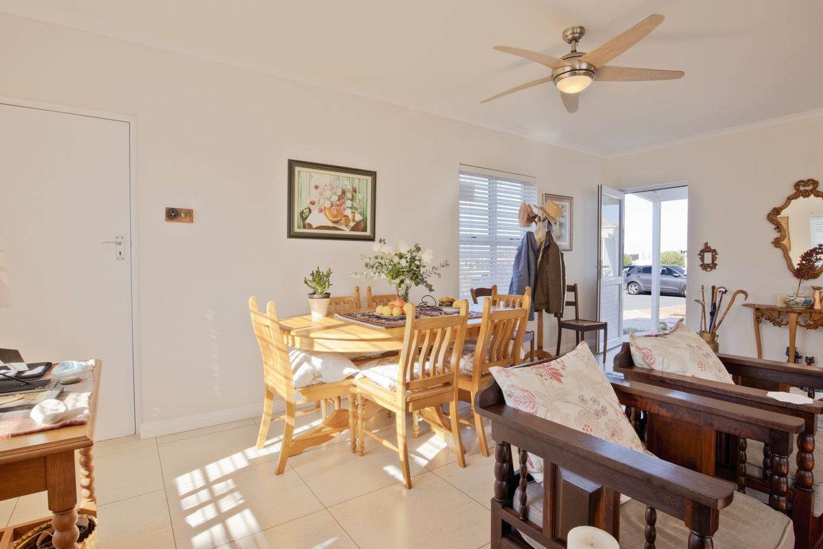 A bright, open-plan living and dining area featuring neutral tiled flooring, a modern ceiling fan, and direct access to the exterior.