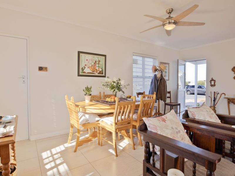 A bright, open-plan living and dining area featuring neutral tiled flooring, a modern ceiling fan, and direct access to the exterior.