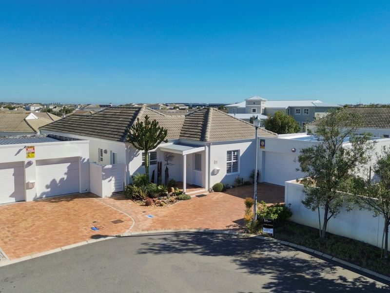 Aerial view of a well-maintained single-story residential property featuring a tiled roof, double garage, and paved driveway in a suburban estate setting.