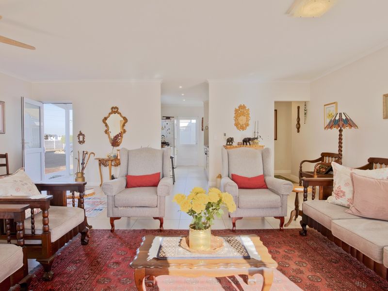 Spacious open-plan living area featuring neutral walls, tiled flooring, and a ceiling fan, with direct access to an outdoor patio area.