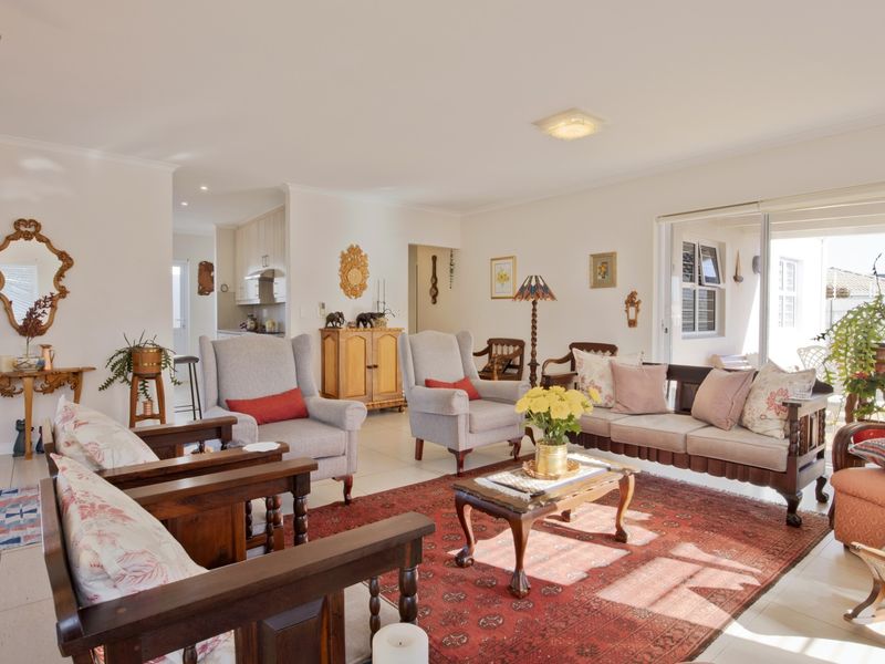 Spacious open-plan living area featuring neutral tiled flooring, abundant natural light from sliding glass doors, and seamless flow into the adjacent kitchen space.