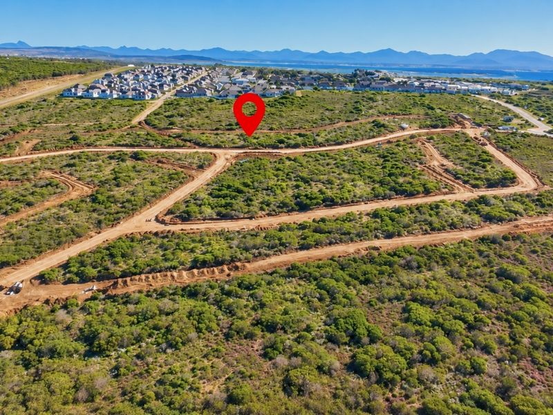 Aerial view of a vacant residential land plot featuring natural vegetation and established dirt access roads within a developing estate.