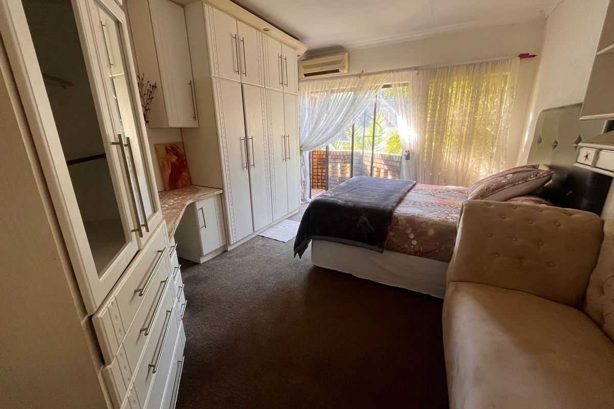 A bedroom featuring built-in cupboards, carpeted flooring, and a sliding glass door providing access to an outdoor area.