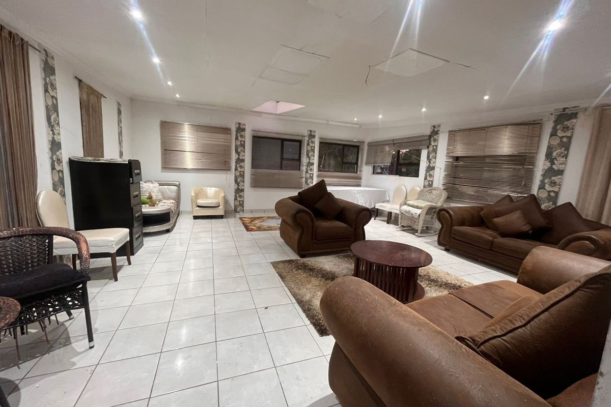 Spacious living area featuring ceramic floor tiles, recessed lighting, and multiple windows with venetian blinds, requiring ceiling repairs.