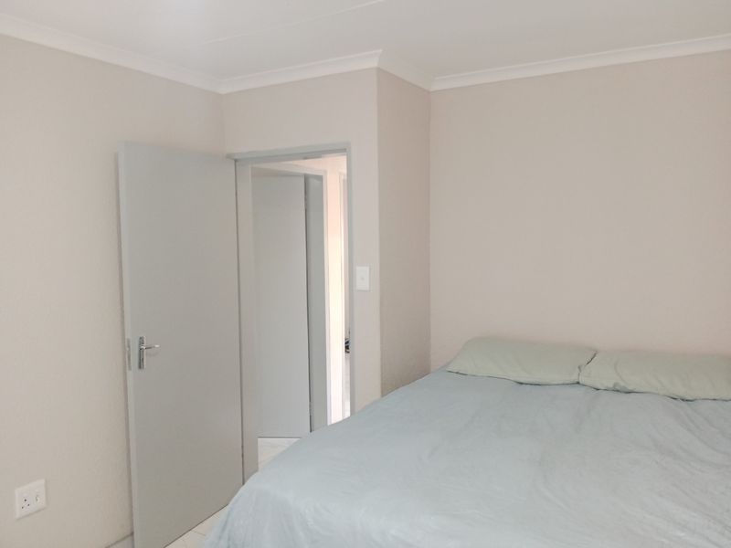 A simple bedroom featuring neutral wall tones, cove cornicing, and a doorway leading to an adjacent space.