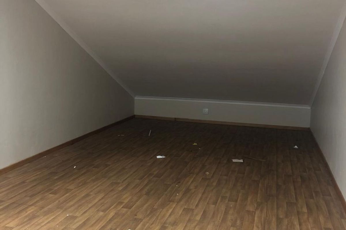 An empty attic-style room featuring laminate flooring and a sloped ceiling, suitable for use as a bedroom or office space.