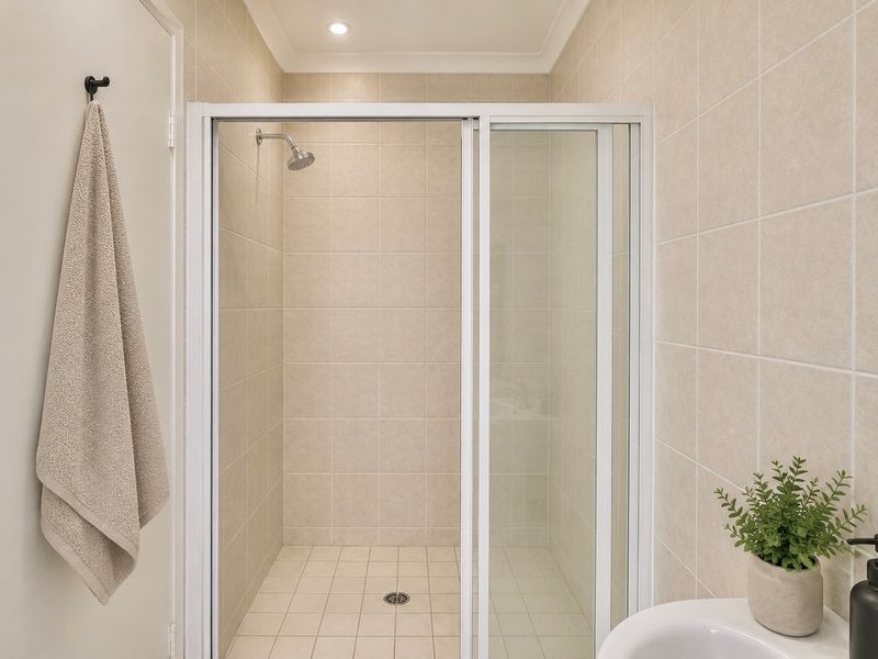 A clean and functional bathroom featuring a tiled shower enclosure with a sliding glass door and recessed lighting.