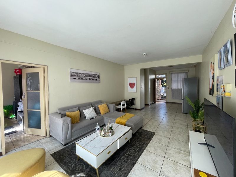 Open plan living area featuring neutral wall tones and tiled flooring, providing a functional space with direct access to the entrance and balcony.