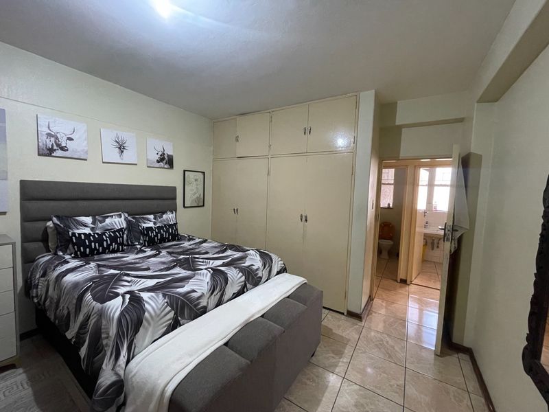 A bedroom featuring built-in cupboards, tiled flooring, and direct access to an en-suite bathroom.