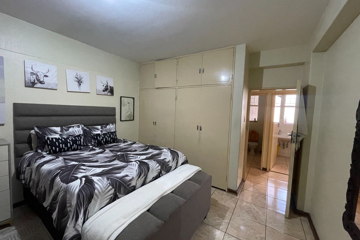 A bedroom featuring built-in cupboards, tiled flooring, and direct access to an en-suite bathroom.