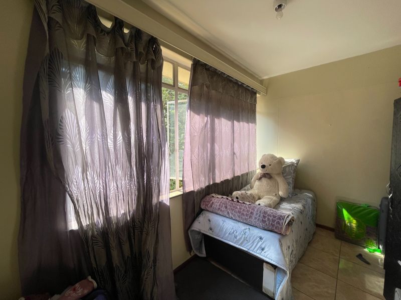 A functional bedroom featuring tiled flooring and a large window that allows for natural light.