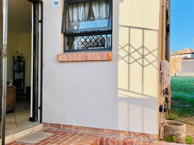 Front entrance area featuring brick steps and patio, with a security gate and window security bars.