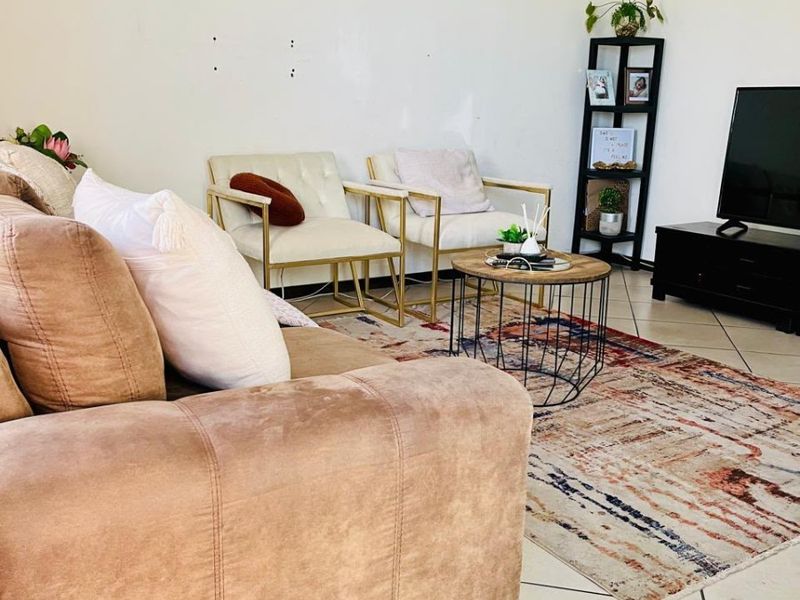 A living room area featuring tiled flooring and plain walls with visible surface imperfections.