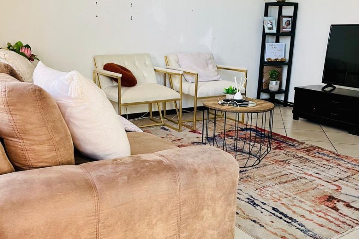 A living room area featuring tiled flooring and plain walls with visible surface imperfections.