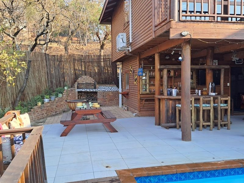 Spacious outdoor patio area featuring a built-in brick braai, a custom wooden bar, and direct access to the swimming pool.
