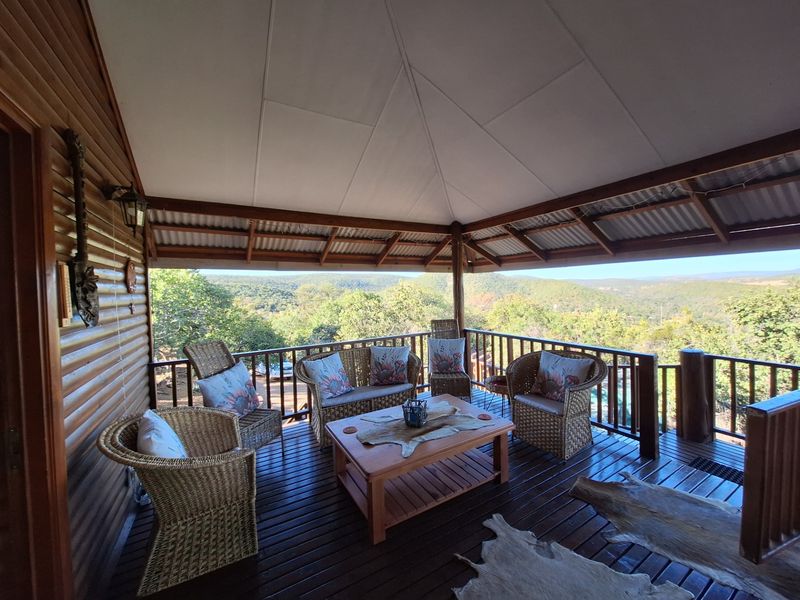 A spacious covered timber deck featuring exposed rafters and panoramic views of the surrounding landscape, providing an ideal outdoor entertainment area.
