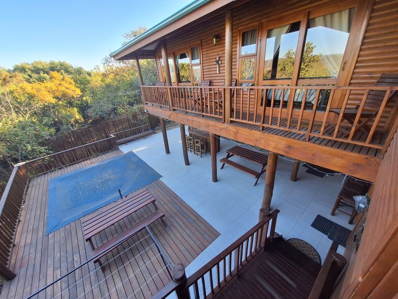 Spacious multi-level outdoor entertainment area featuring a covered tiled patio, elevated wooden deck, and a swimming pool with a safety cover.