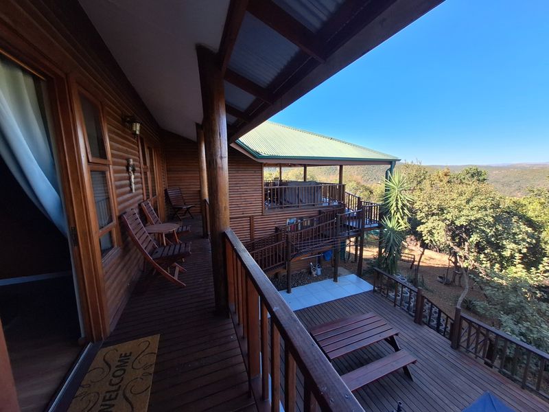 Spacious elevated timber balcony featuring wooden decking and balustrades, offering expansive views of the surrounding natural landscape.