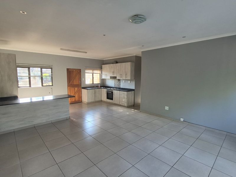 Spacious open-plan living area featuring a modern kitchen with built-in cabinetry, breakfast bar, and tiled flooring throughout.