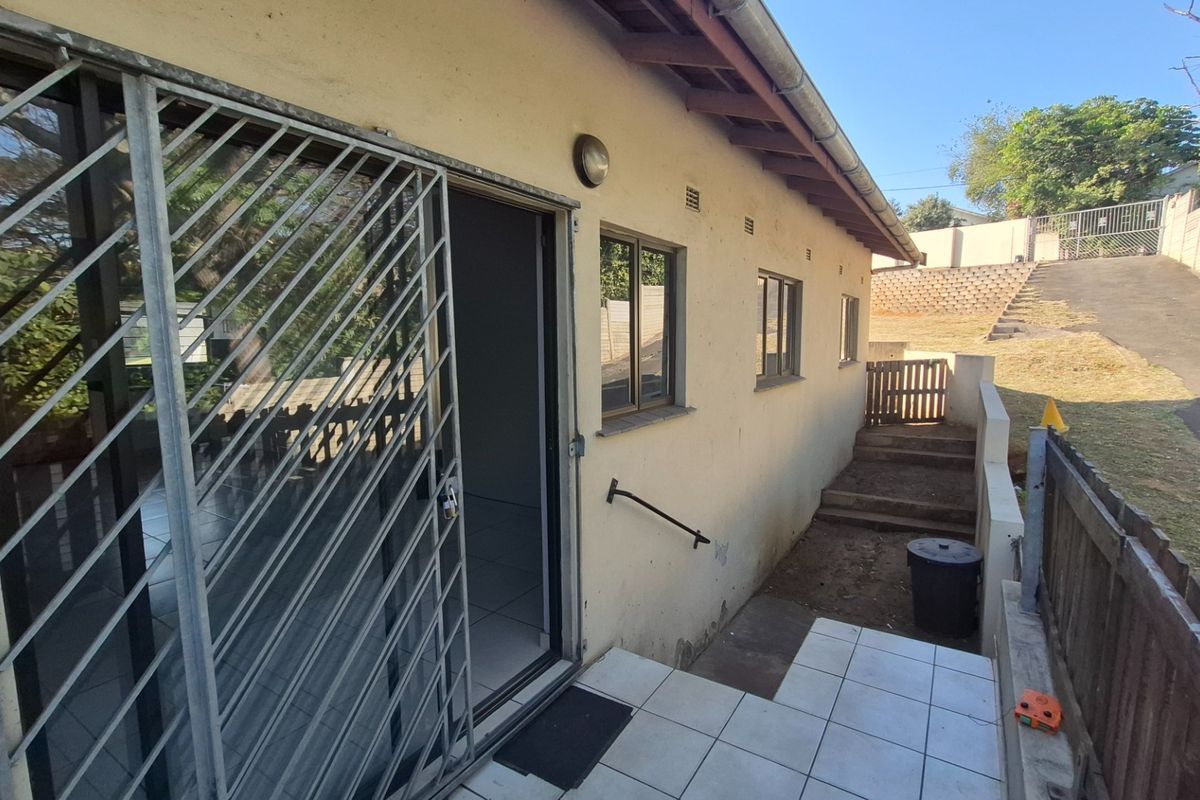 Rear exterior view showing a tiled patio area, security gate, and access steps leading to the backyard and driveway.