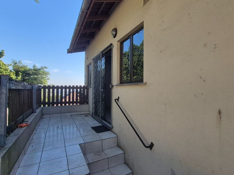 A tiled outdoor patio area featuring a security gate, handrail, and timber fencing, providing access to the home's interior.