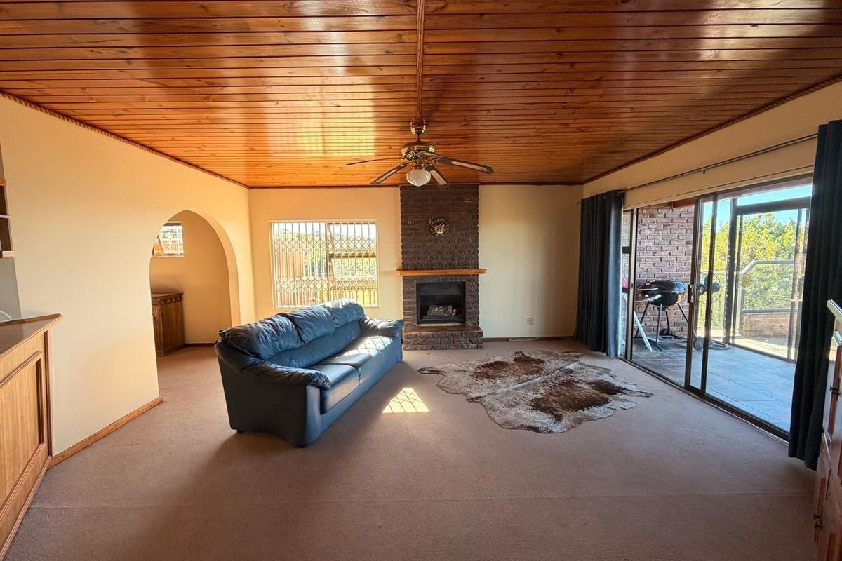 Spacious living room featuring a timber-clad ceiling, a brick fireplace, and large sliding glass doors providing access to the outdoor patio area.