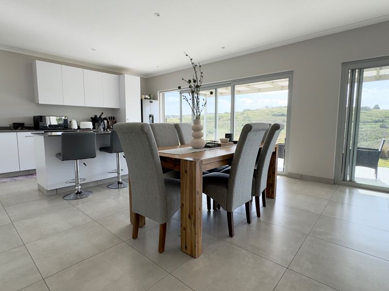 Spacious open-plan kitchen and dining area featuring modern cabinetry, a central island, and large sliding doors leading to an outdoor patio with scenic views.