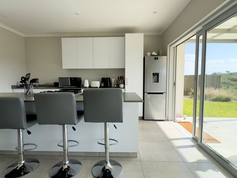 Modern kitchen featuring a central island with stone countertops, sleek cabinetry, and large sliding glass doors providing seamless access to the outdoor patio area.