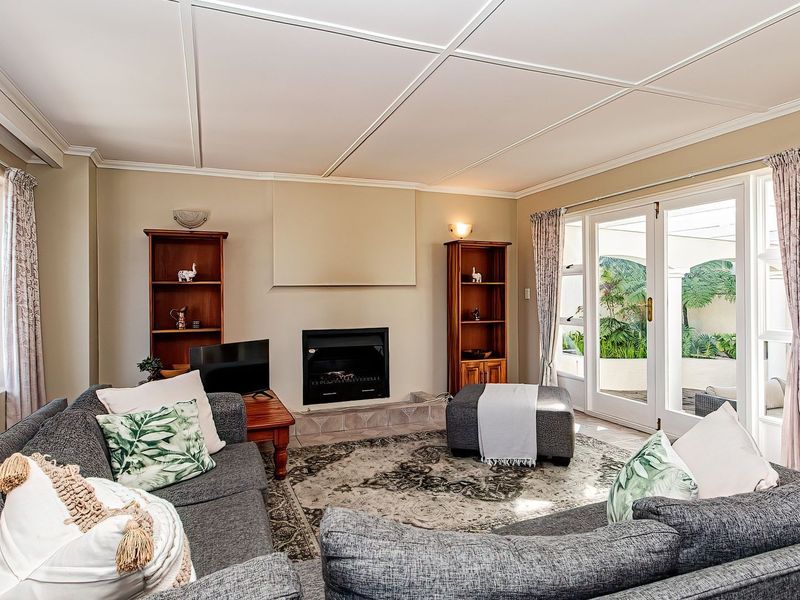 Spacious living room featuring a built-in fireplace, tiled ceiling panels, and double glass doors providing direct access to the outdoor patio area.