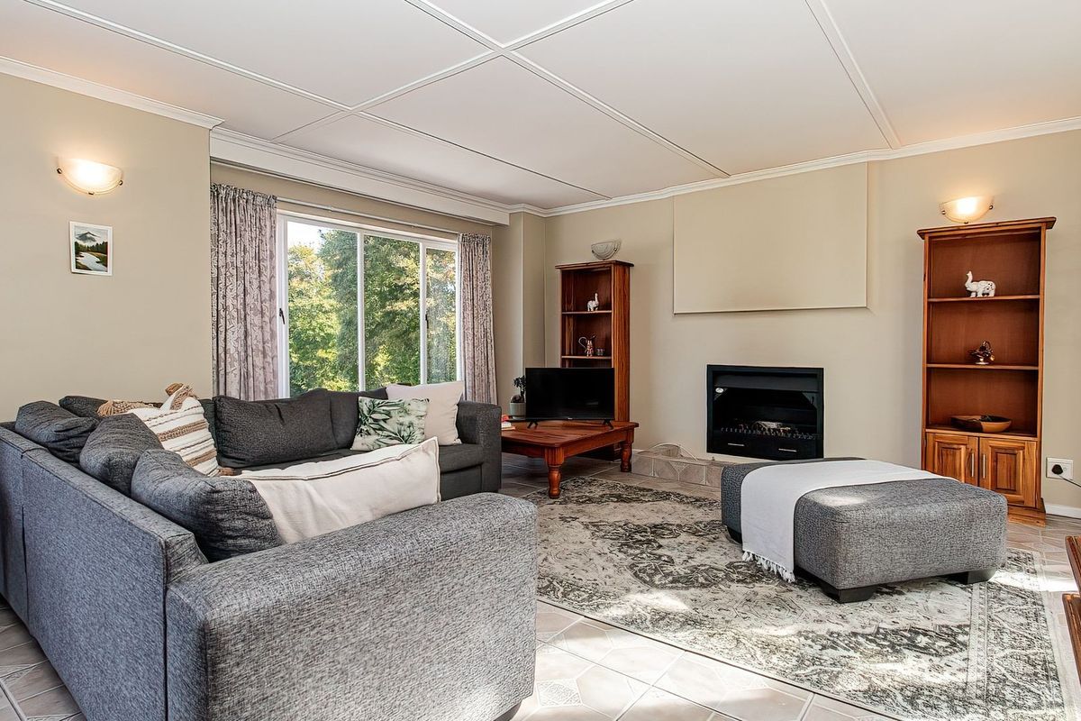 A comfortable living room featuring a built-in fireplace, tiled flooring, and large sliding glass doors that provide natural light and garden views.