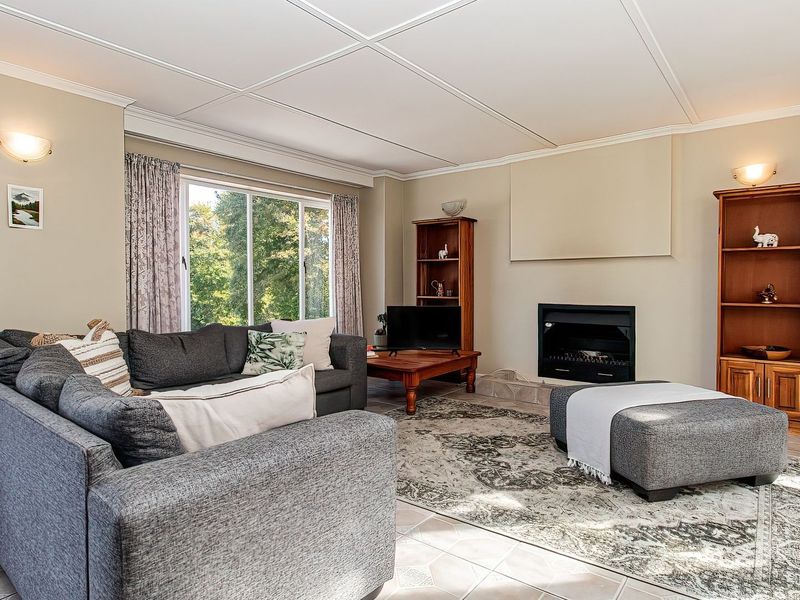 A comfortable living room featuring a built-in fireplace, tiled flooring, and large sliding glass doors that provide natural light and garden views.