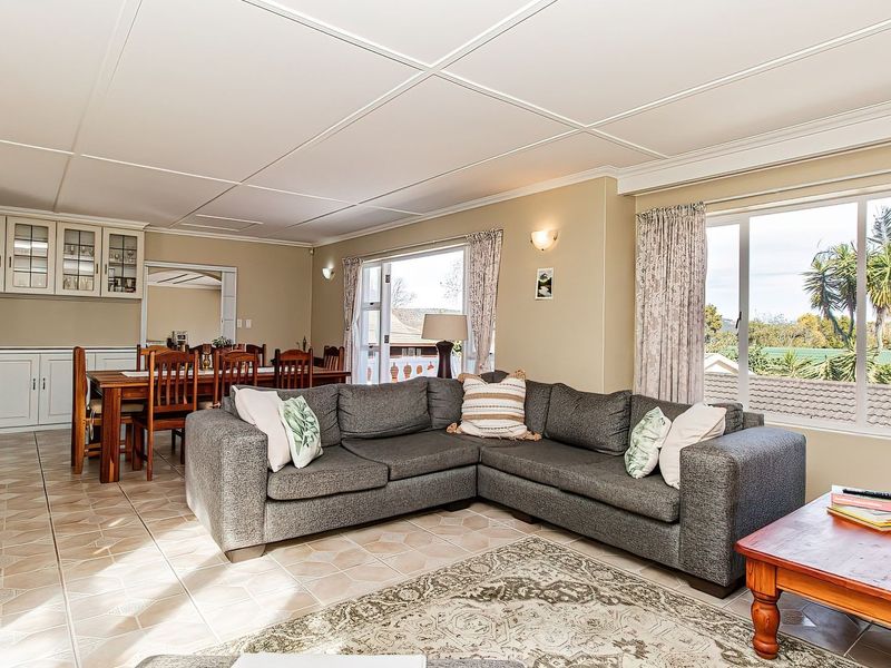 Spacious open-plan living and dining area featuring tiled flooring, built-in cabinetry with a wine rack, and large windows providing natural light.