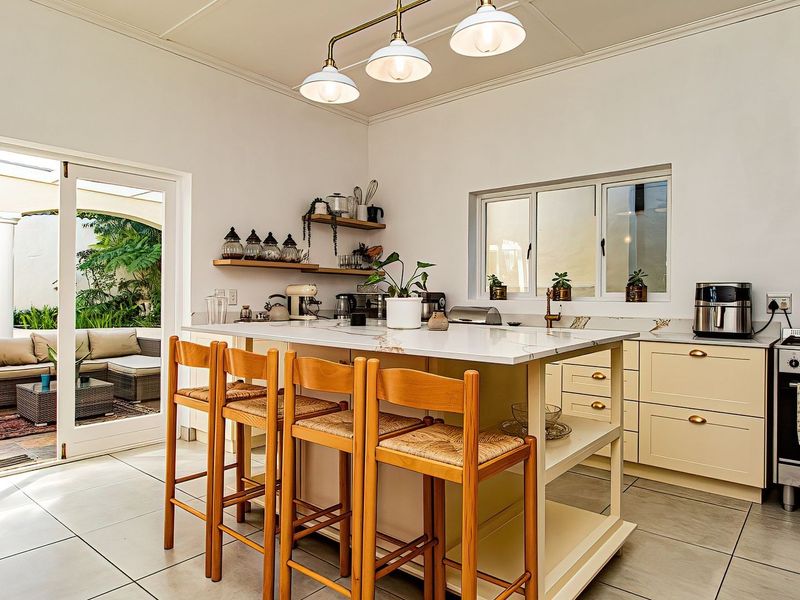 A bright, modern kitchen featuring a central island with stone countertops, ample cabinetry, and direct access to an outdoor patio area.