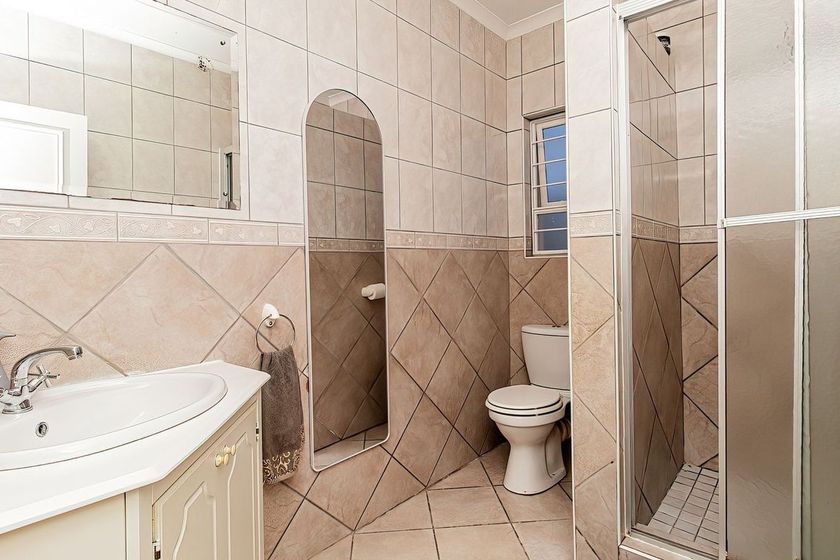 A functional bathroom featuring a vanity cabinet with a ceramic basin, a toilet, and a separate shower enclosure with tiled finishes throughout.