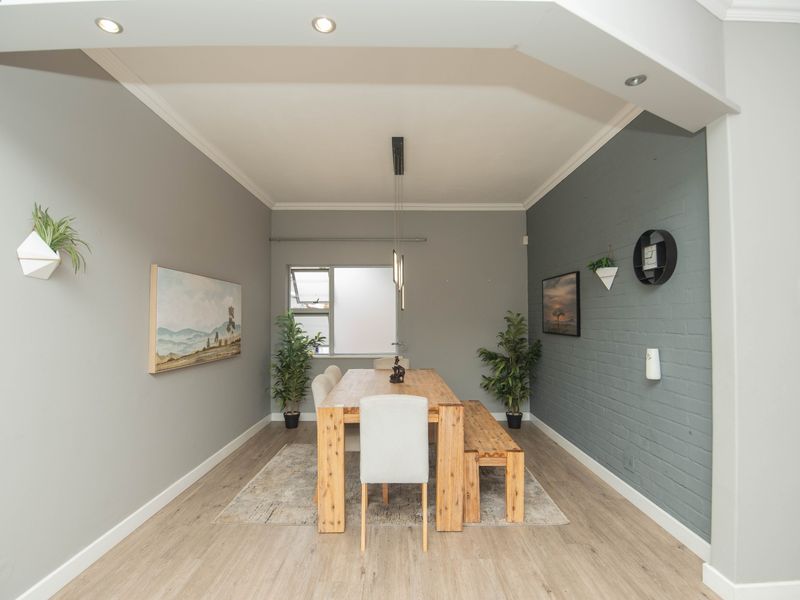 A well-maintained dining room featuring a painted brick accent wall, modern recessed lighting, and durable laminate flooring.