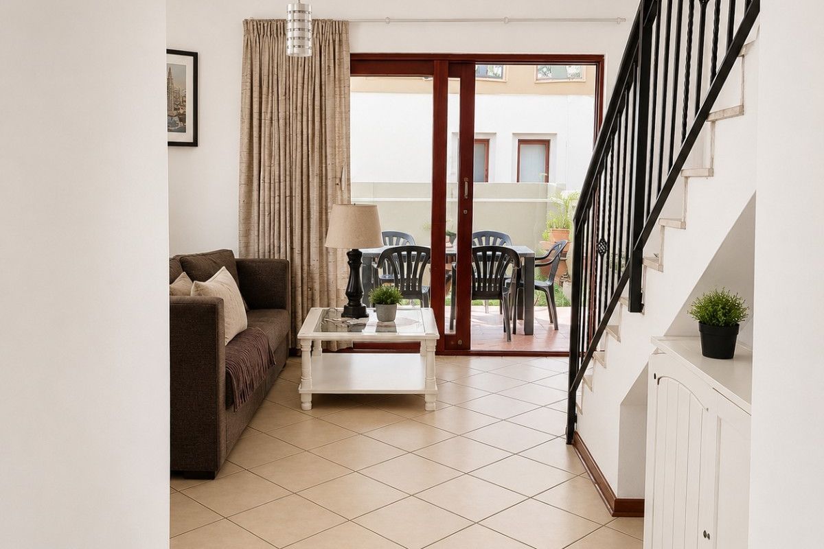 Bright living area featuring tiled flooring, a staircase with a metal balustrade, and sliding glass doors providing access to the patio.