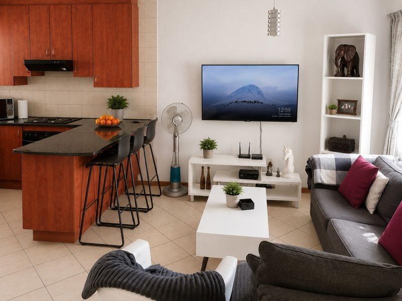 Open-plan living area featuring a kitchen with wood-finish cabinetry, granite countertops, and tiled flooring, seamlessly connected to the lounge space.