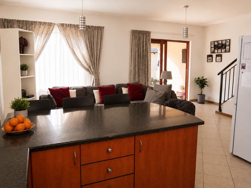 Open plan living area featuring a kitchen island with granite countertops, tiled flooring, and direct access to an outdoor patio area.