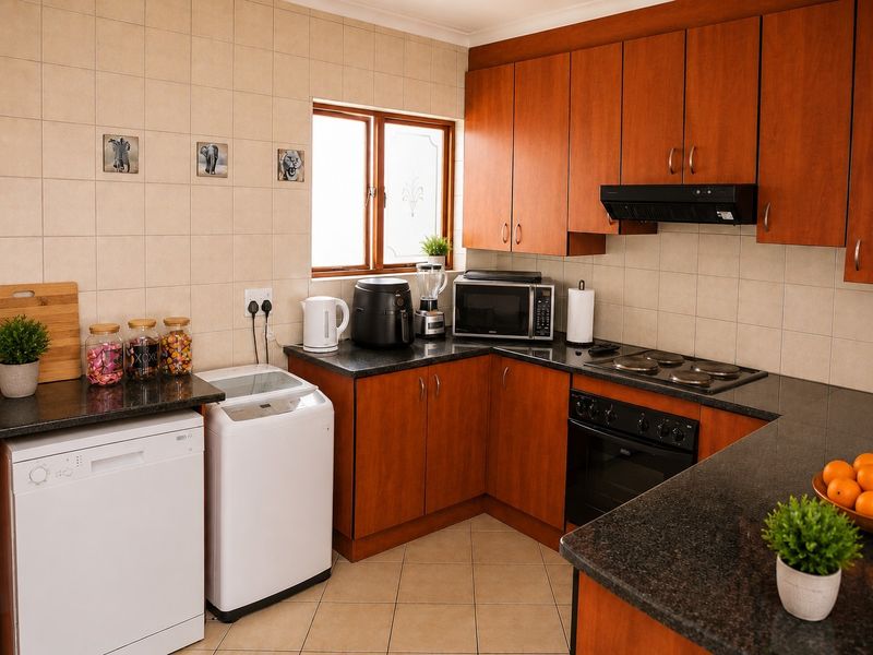 A functional kitchen featuring warm-toned laminate cabinetry, granite countertops, a built-in oven with hob, and tiled splashbacks.