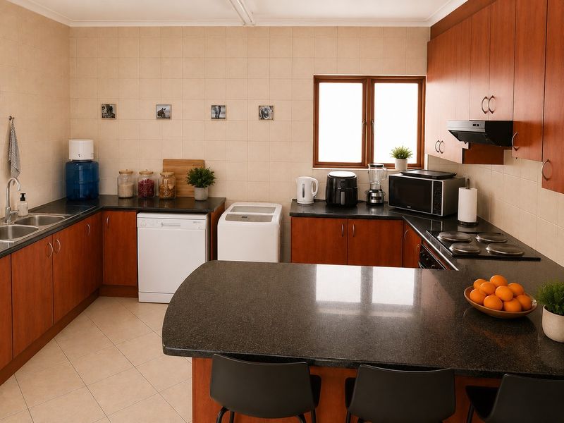 A functional kitchen featuring wood-finish cabinetry, granite countertops, a double sink, and an integrated electric hob with an extractor fan.