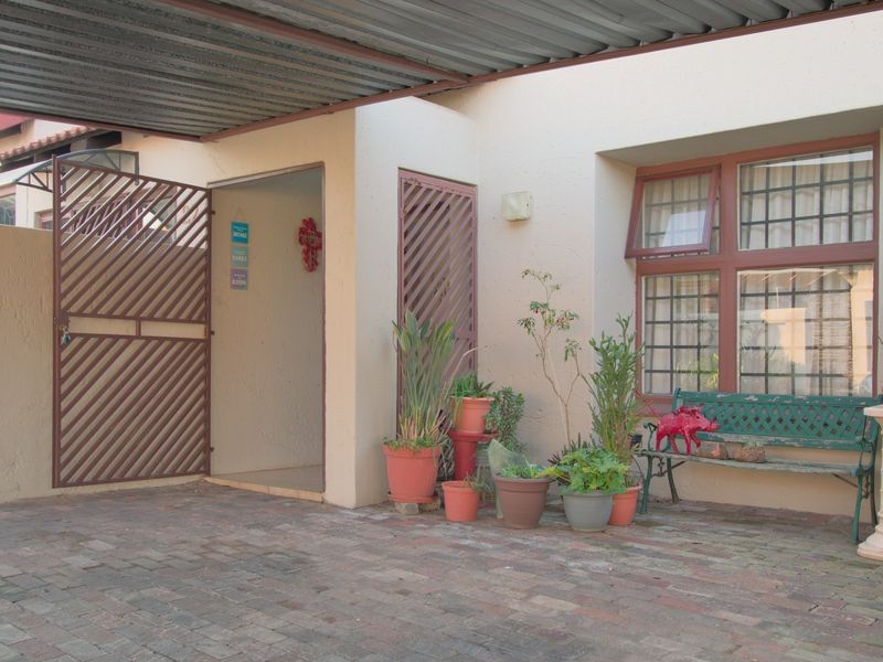 Covered front entrance area featuring brick paving, a security gate, and window security bars, providing a functional and secure entry point to the townhouse.