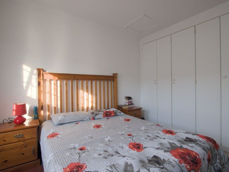 A functional bedroom featuring white walls, neutral flooring, and ample built-in cupboard storage space.