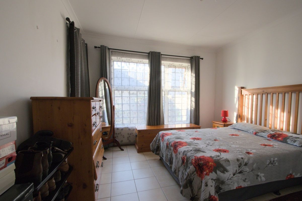 A functional bedroom featuring tiled flooring and large windows with curtain rails, providing natural light and a neutral foundation for interior design.